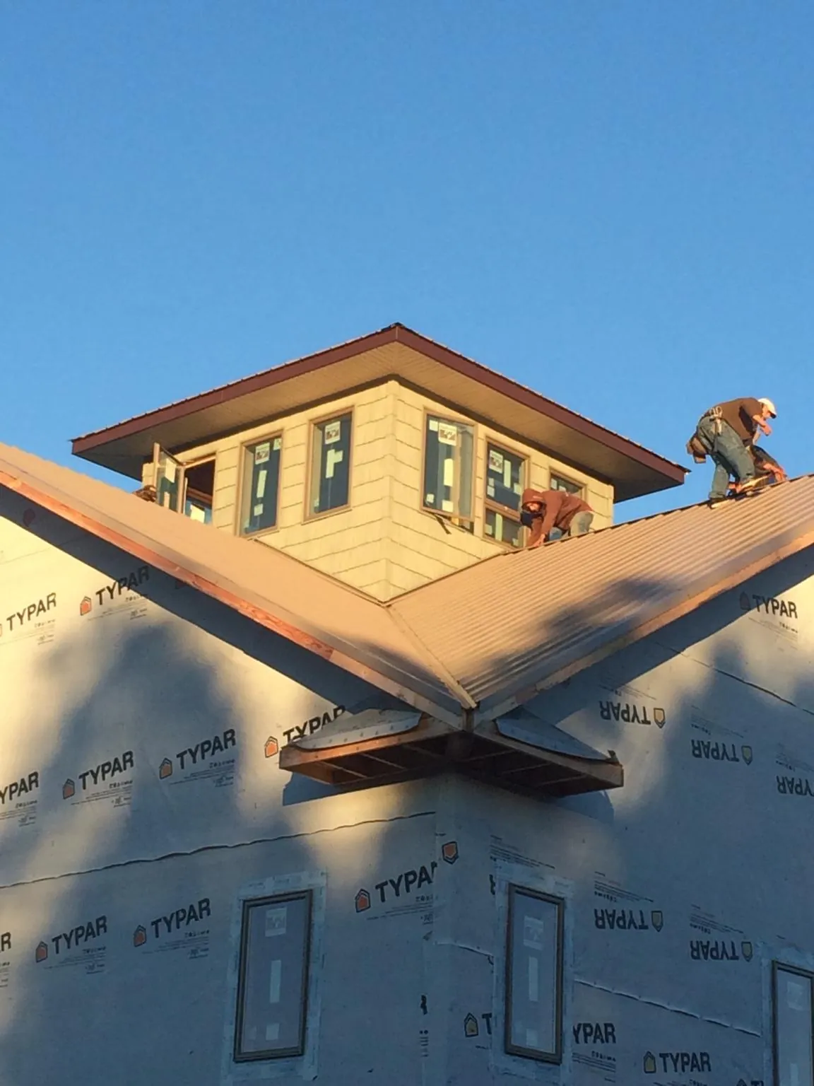 Roofers working around a rooftop cupola on a new metal roof at sunset — Roof Waterproofing in Gresham by Roofing Brothers